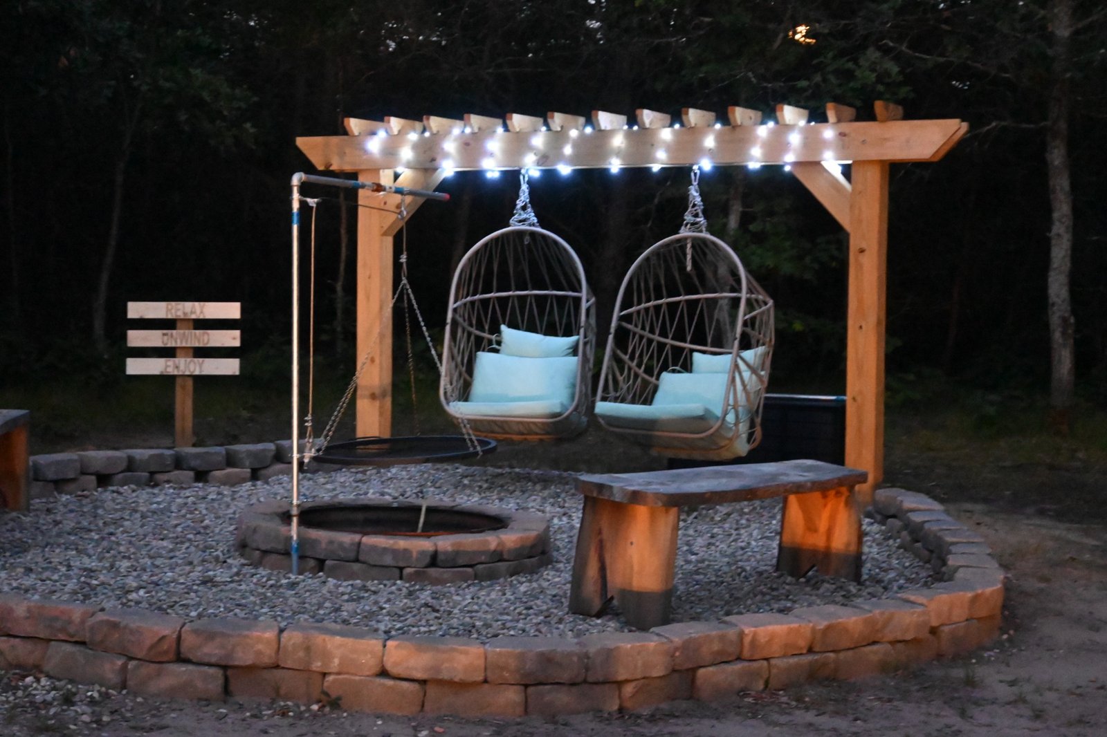 Private fire pit and illuminated pergola with Relax Unwind Enjoy sign at Kirby Land